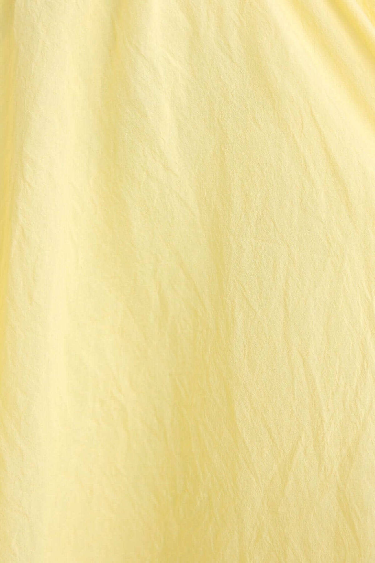 Textured close-up of lightweight yellow fabric used in the Civita Maxi Dress, showcasing its soft, flowing quality.