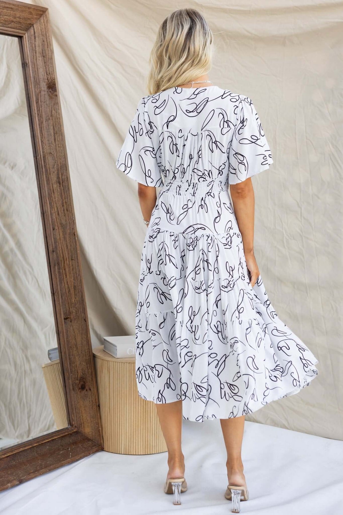 Woman wearing a Hope Filled Midi Dress, showcasing a button-down front and a shirred elastic waist.