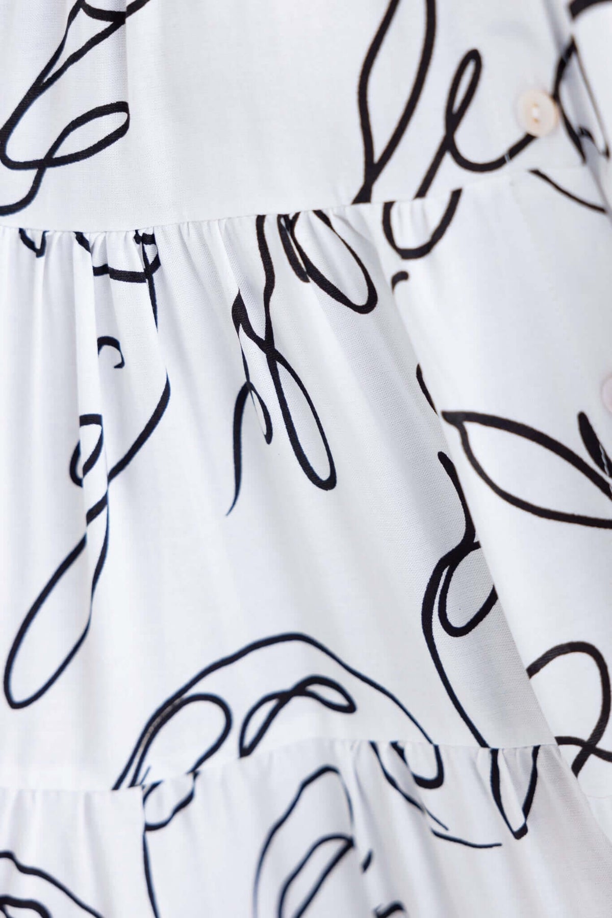 Close-up of the Hope filled Midi Dress featuring a white fabric with black abstract patterns and button details.