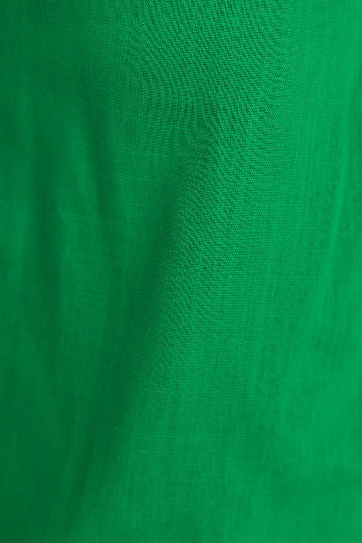 Close-up of vibrant green linen fabric, showcasing a textured, lightweight material ideal for stylish clothing.