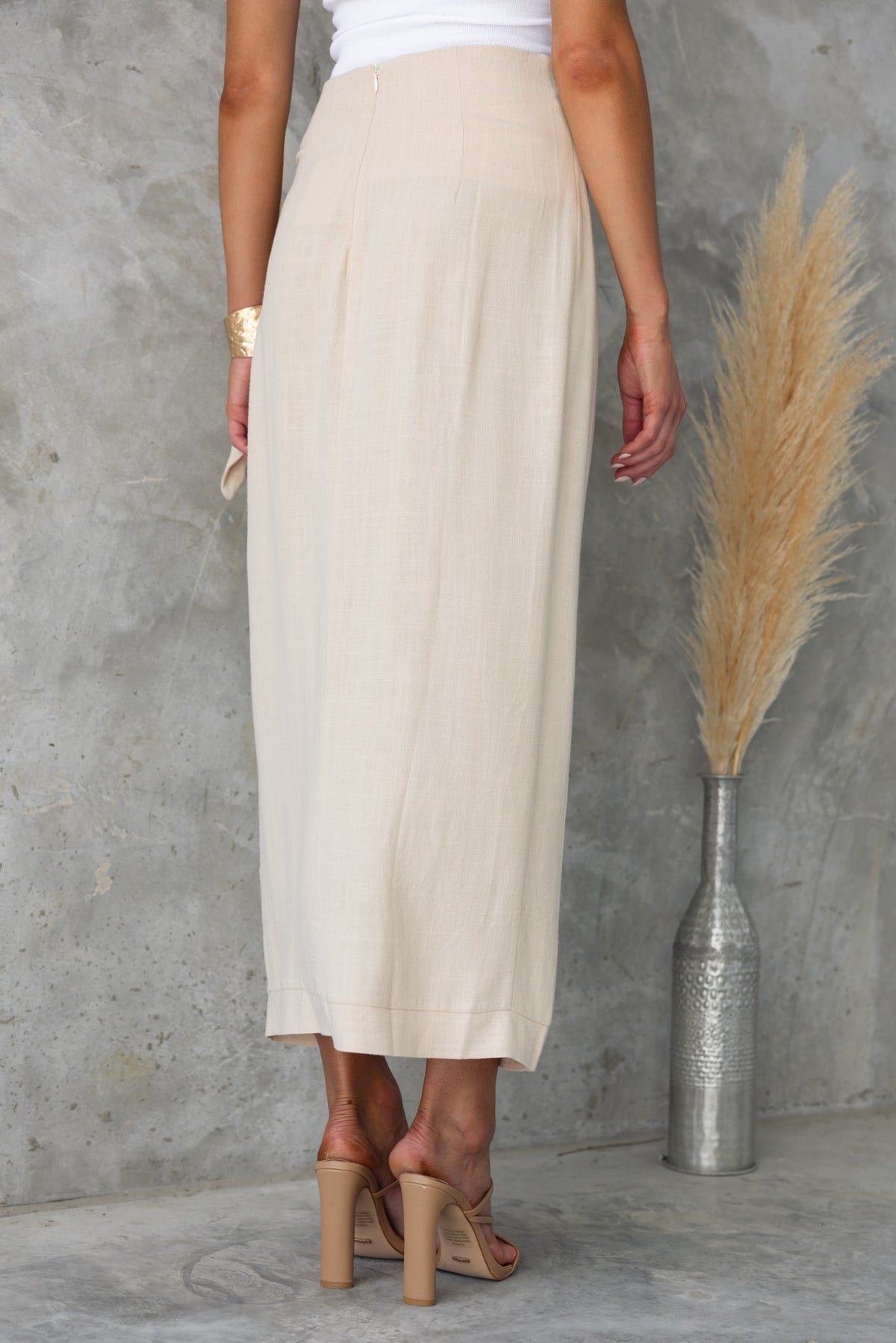 Back view of the Tahnee Maxi Skirt in cream, featuring an asymmetric hem and side tie detail.