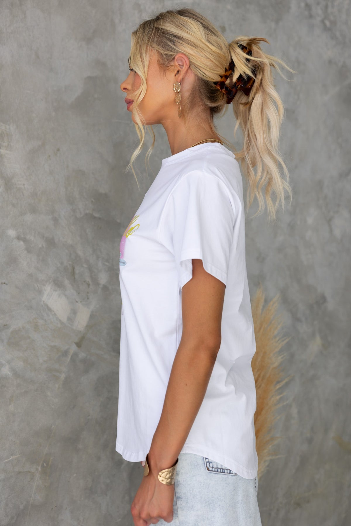 Model wearing a white 'Limocello Spritz' print tee with round neckline and soft cotton feel.