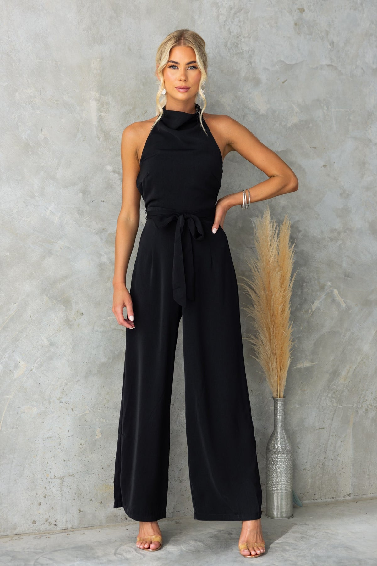 Elegant black Skyler jumpsuit featuring a high neckline, removable tie, and fitted design, perfect for versatile styling.