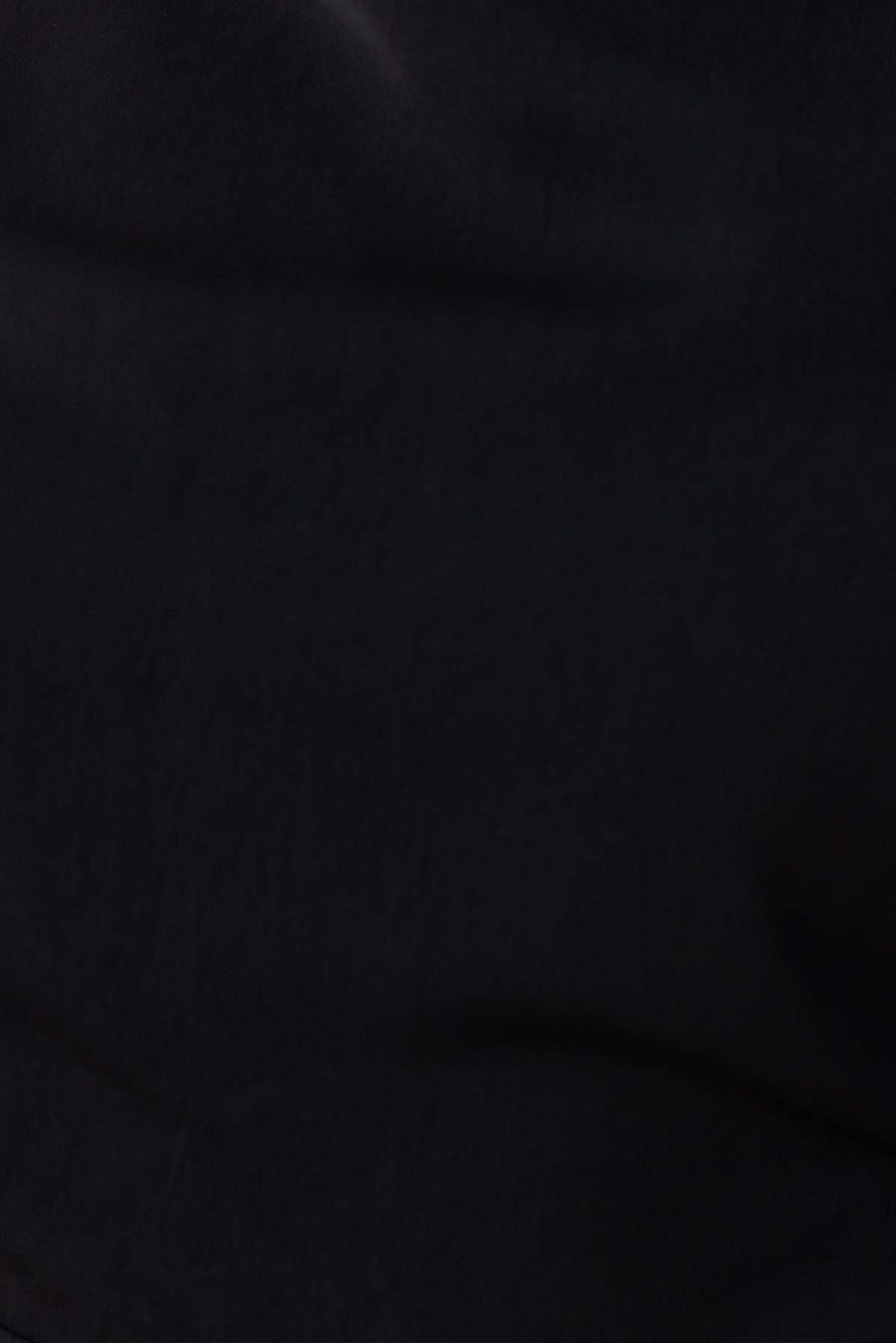 Close-up of black fabric texture from the Skyler Jumpsuit, featuring smooth, non-stretch material.