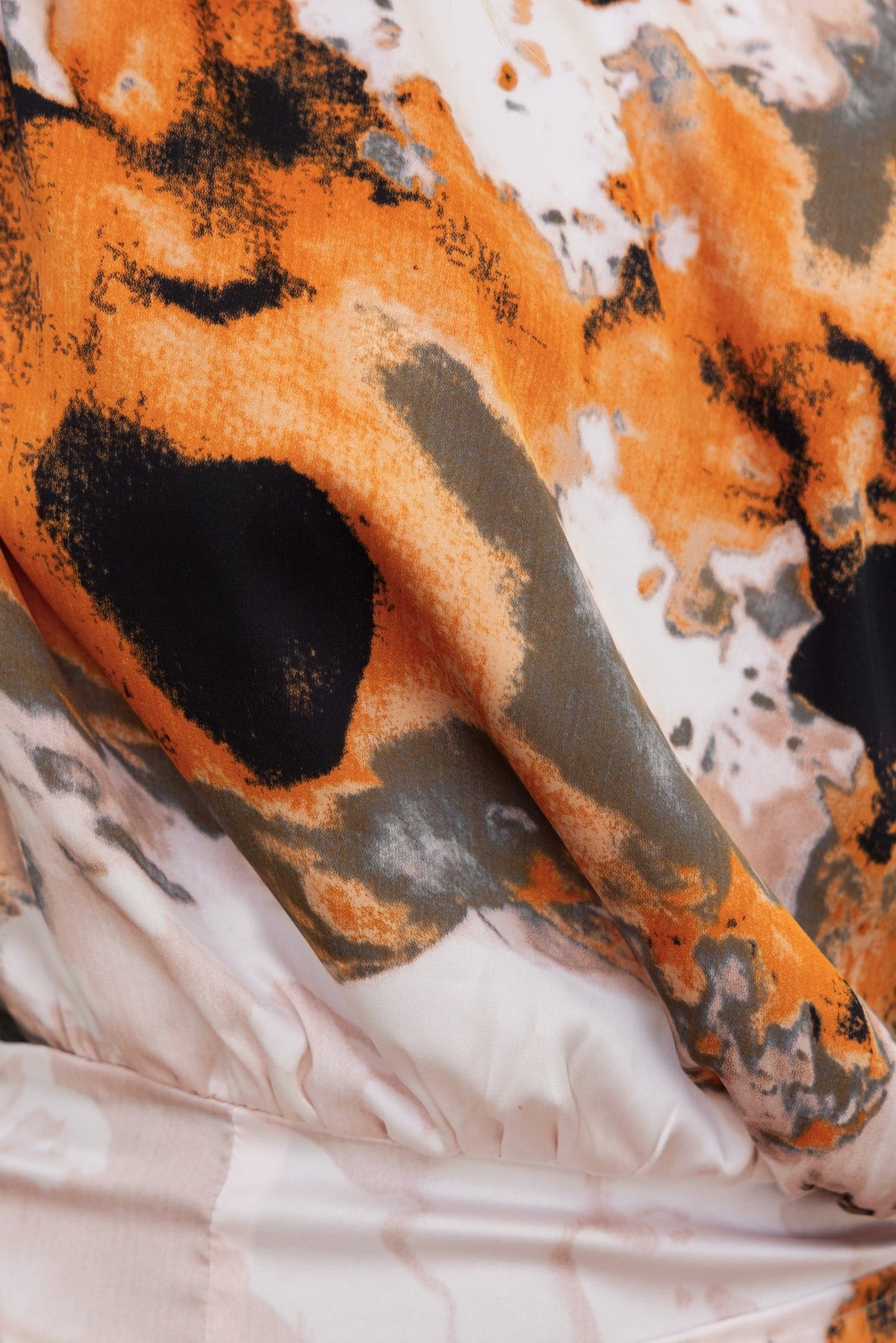Close-up of Ayanna Dress fabric featuring vibrant orange and black abstract print on soft satin material.