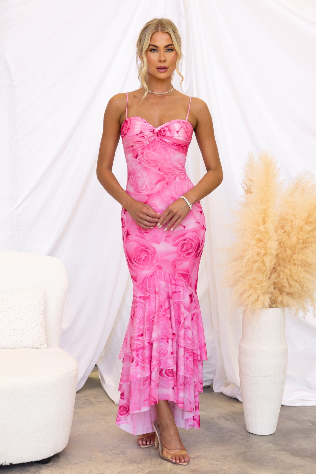 Model wearing Qasila bodycon maxi dress with pink rose print and ruffle hem, showcasing adjustable straps and mesh overlay.