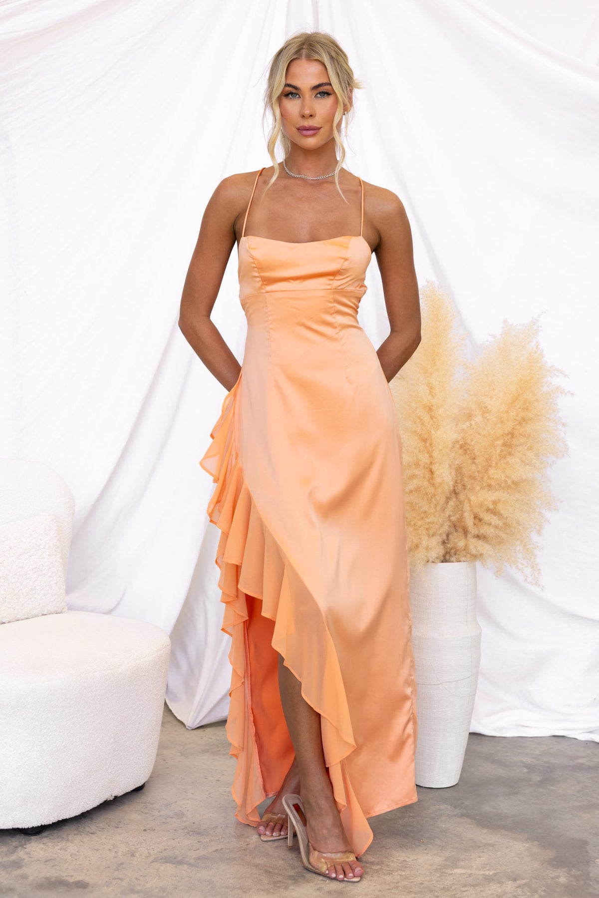 Elegant peachy maxi dress with ruffle detail and adjustable straps, showcased against a soft backdrop.