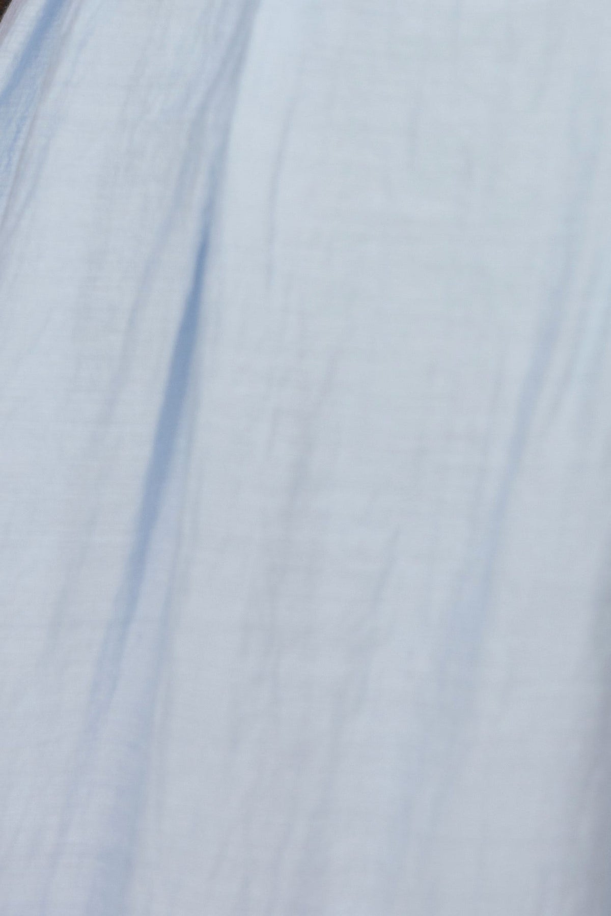 Close-up of soft blue fabric of the Elettra Maxi Dress, showcasing its lightweight and airy texture.