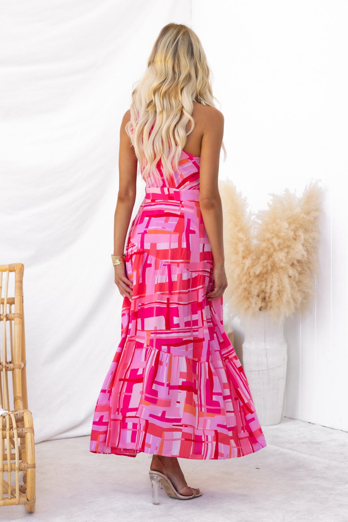 Model wearing a colorful Tovah maxi dress with a one-shoulder design and a flared hem, showcasing back view.