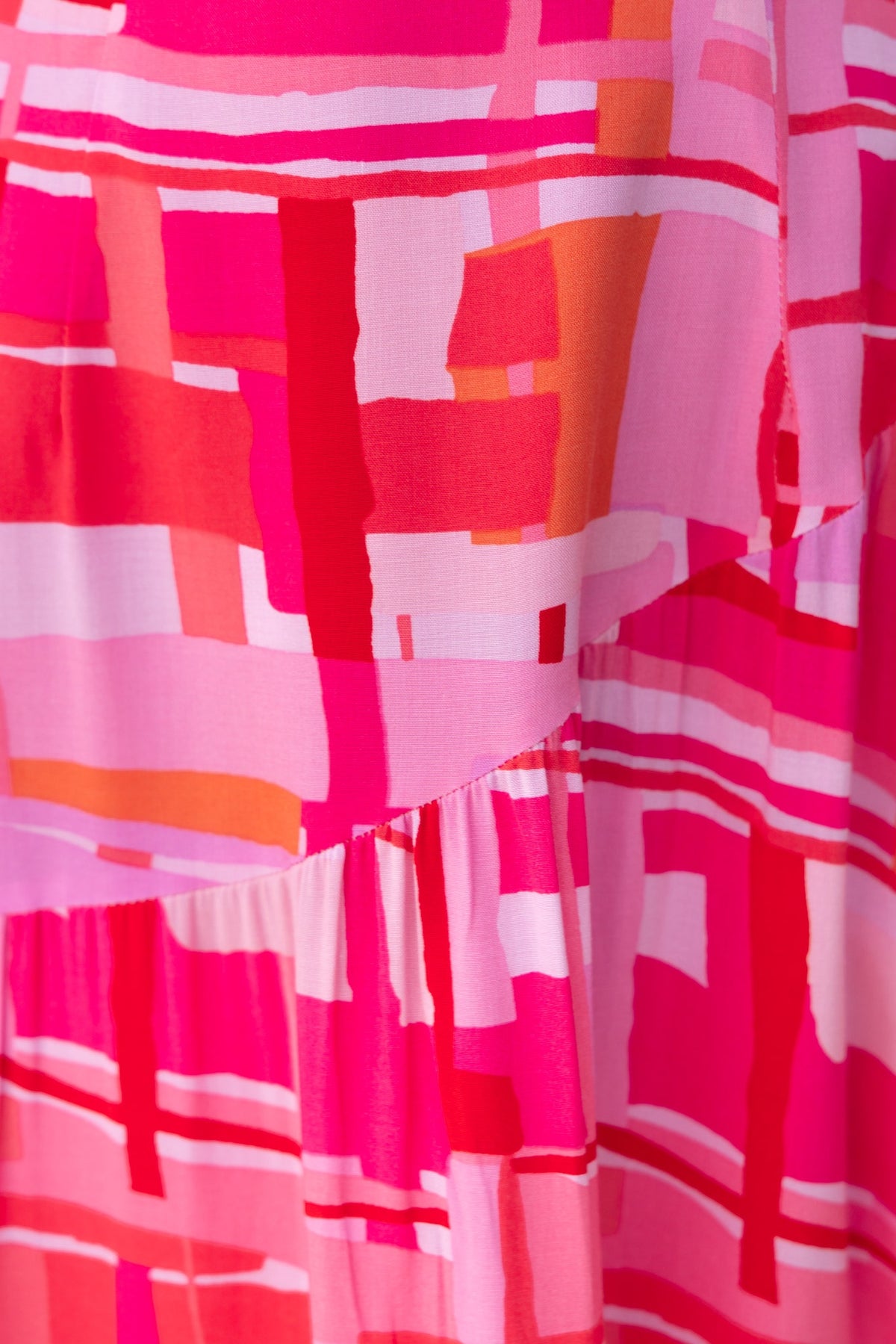 Close-up of the Tovah Maxi Dress featuring a vibrant multi-colour geometric pattern in pink and orange hues.