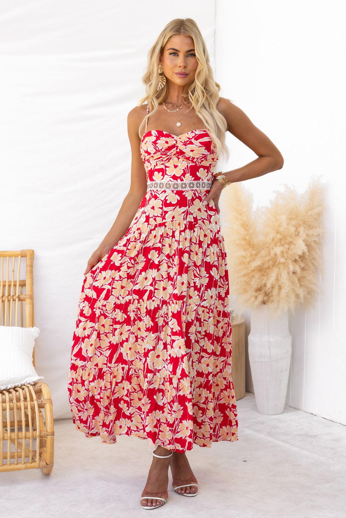 Model wearing a red floral print Vani maxi dress with adjustable straps and lace detail in a stylish setting.