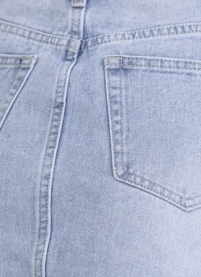 Close-up of denim skirt back pockets, showcasing light wash and classic stitching detailing.