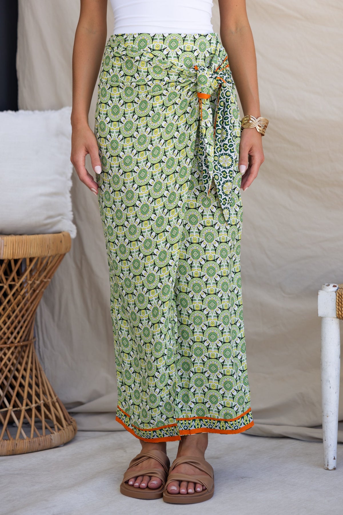 Model wearing a green Tahnee Maxi Skirt with a tie at the side and asymmetric hemline, styled with sandals.