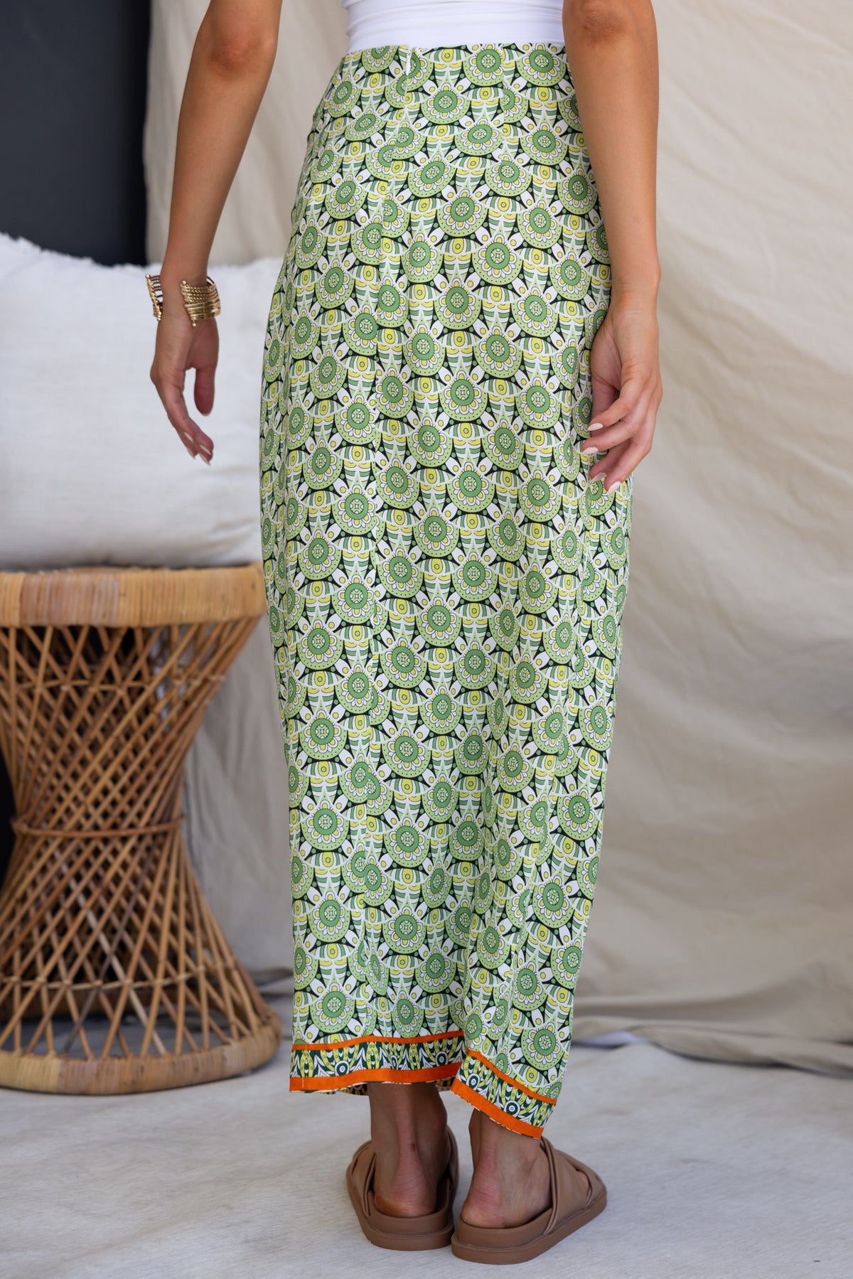 Woman wearing Tahnee maxi skirt with green floral pattern, showcasing asymmetric hem and tied side detail.