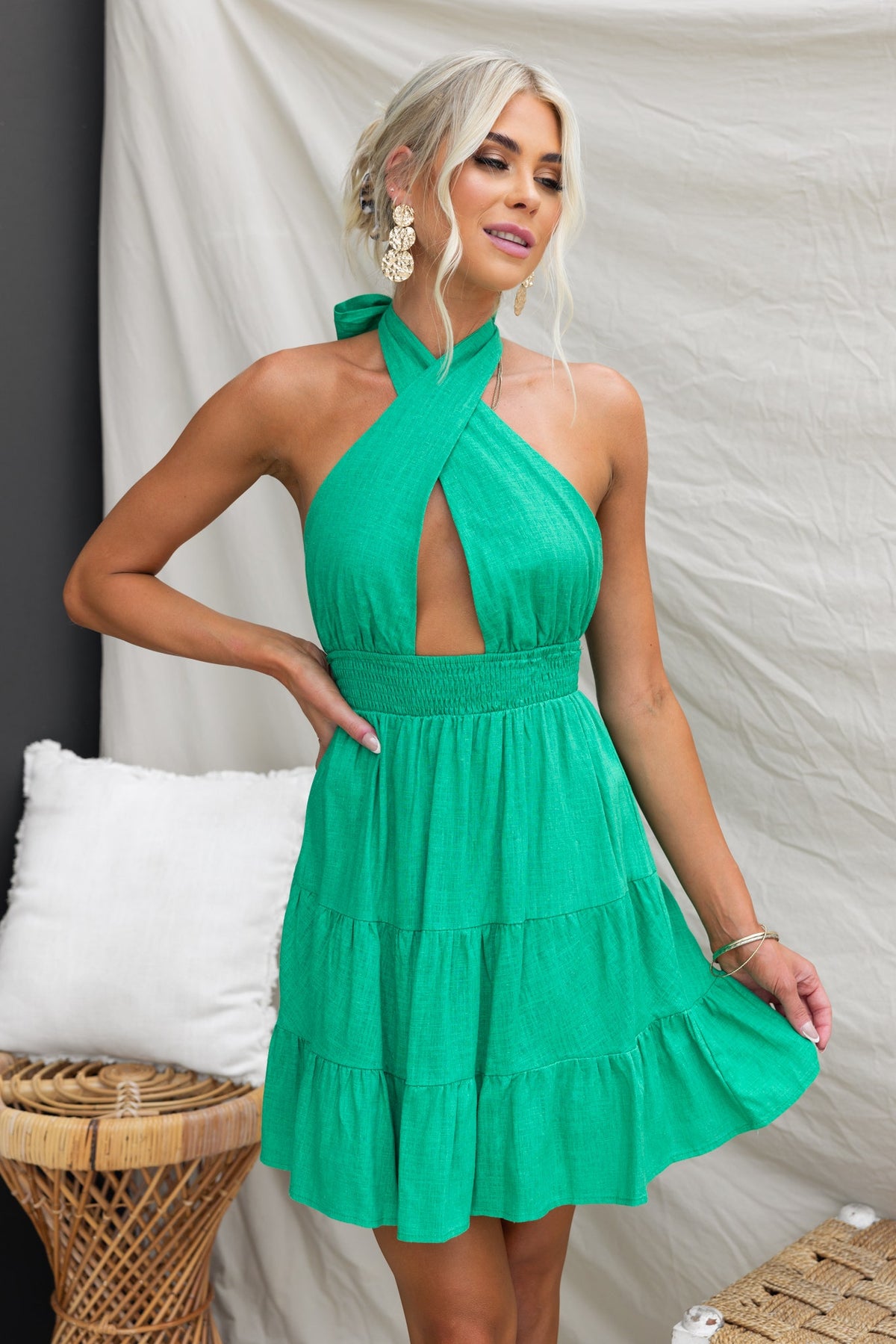Model wearing a green Alaria Dress with an adjustable tie neckline and tiered skirt in a stylish setting.