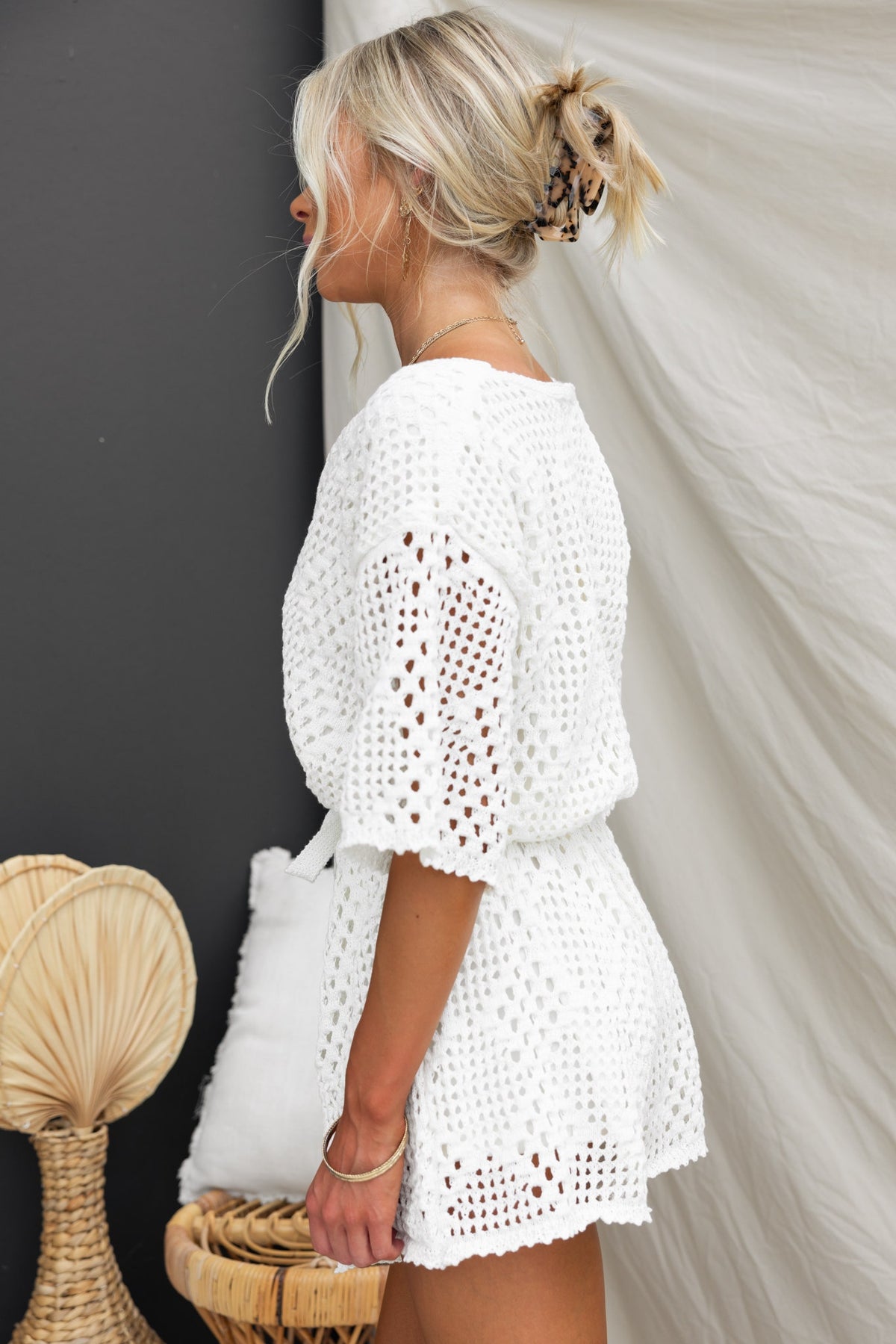 Stylish woman wearing a Momo Playsuit made of crochet material, featuring a buttoned bust and removable tie.