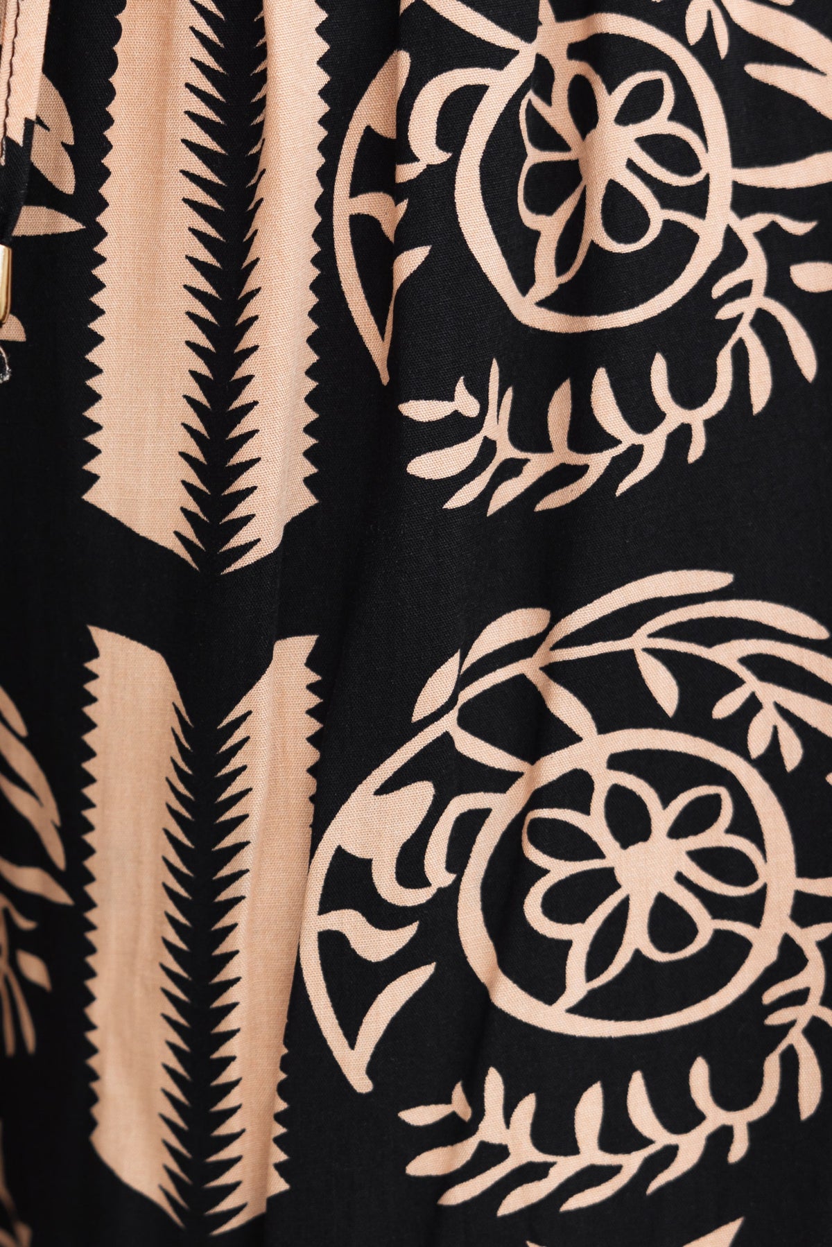 Close-up of black fabric with intricate cream floral and geometric patterns featuring a modern design.