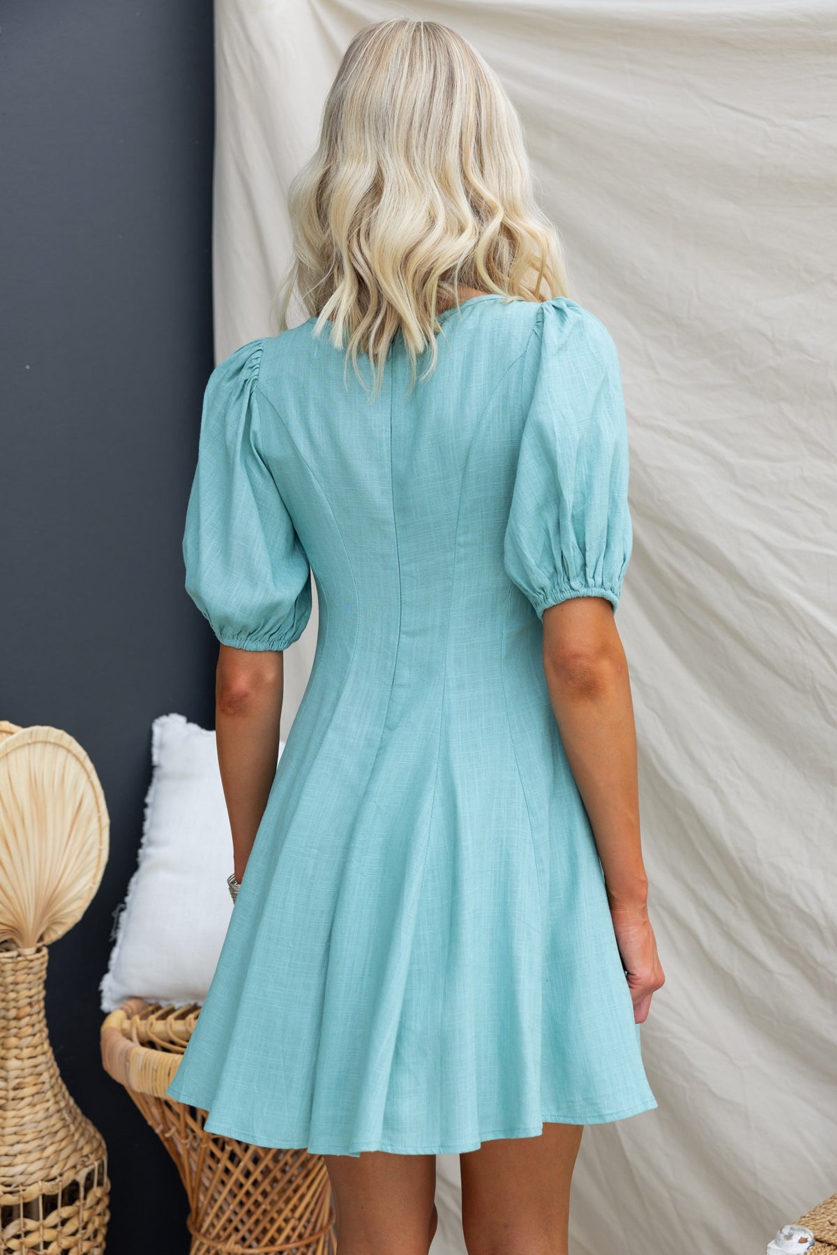Back view of a light blue Morado Dress featuring puff sleeves and a flared skirt, styled for a casual look.