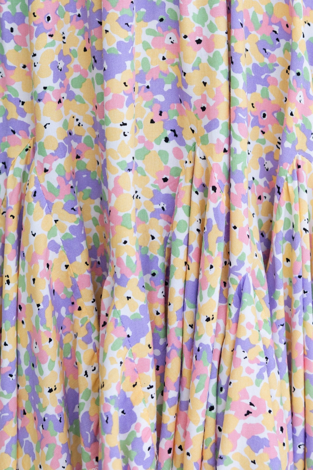 Floral print fabric featuring pastel colors in shades of yellow, pink, green, and purple, perfect for a dress.