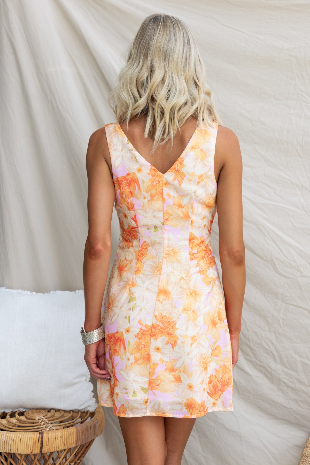 Back view of a floral Carmine dress with a V-neckline and a vibrant orange pattern, perfect for warm seasons.