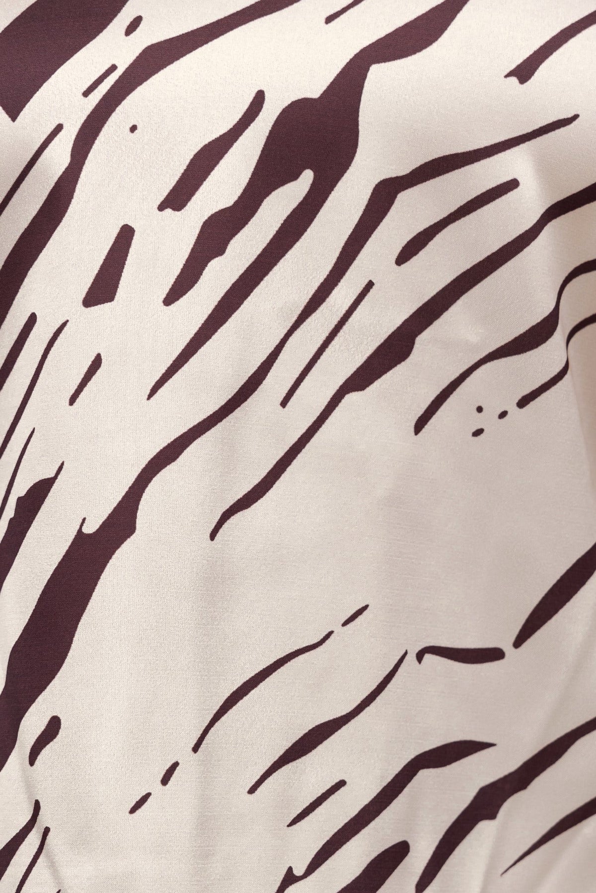 Close-up of abstract print fabric with brown stripes on a cream background, showcasing satin look and feel.