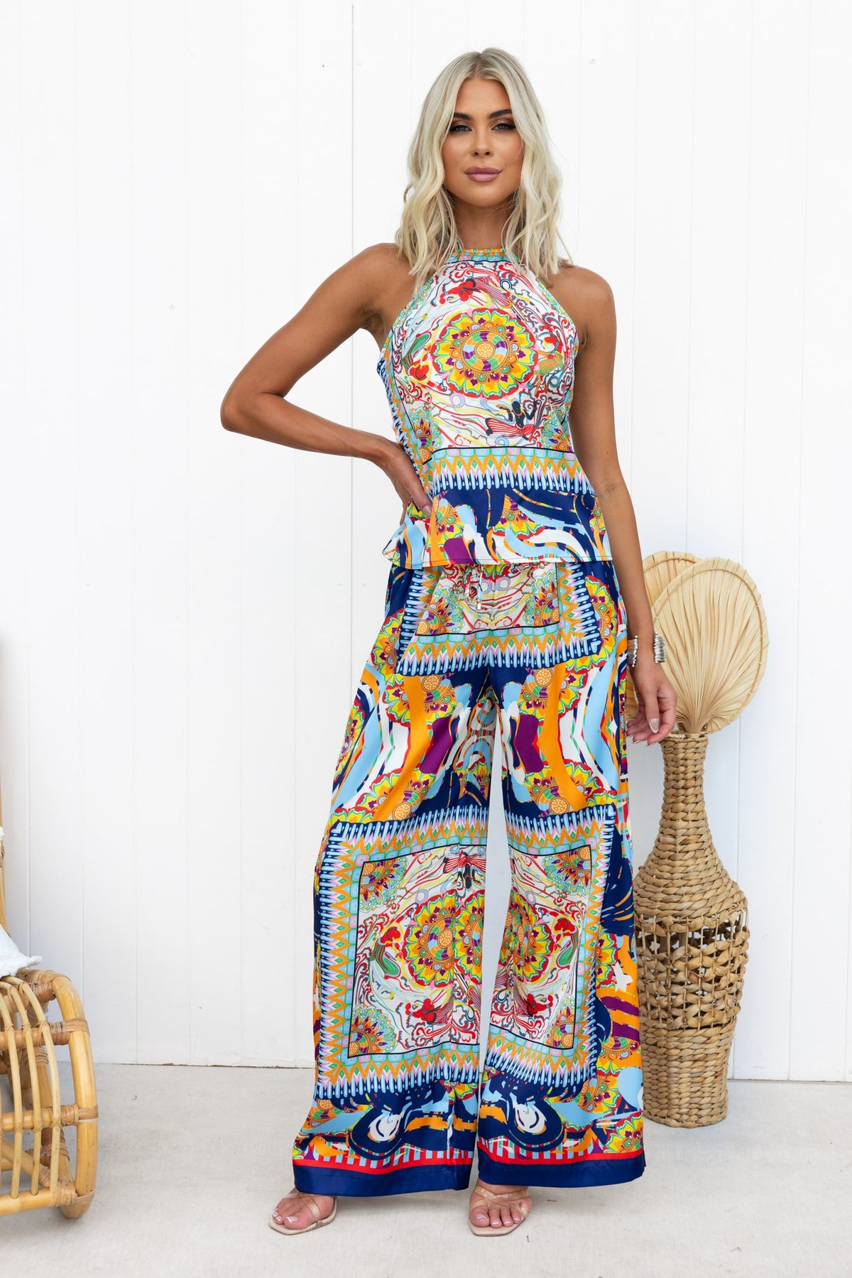 Model wearing a colorful abstract print halter top and wide-leg pants, showcasing a vibrant bohemian style.