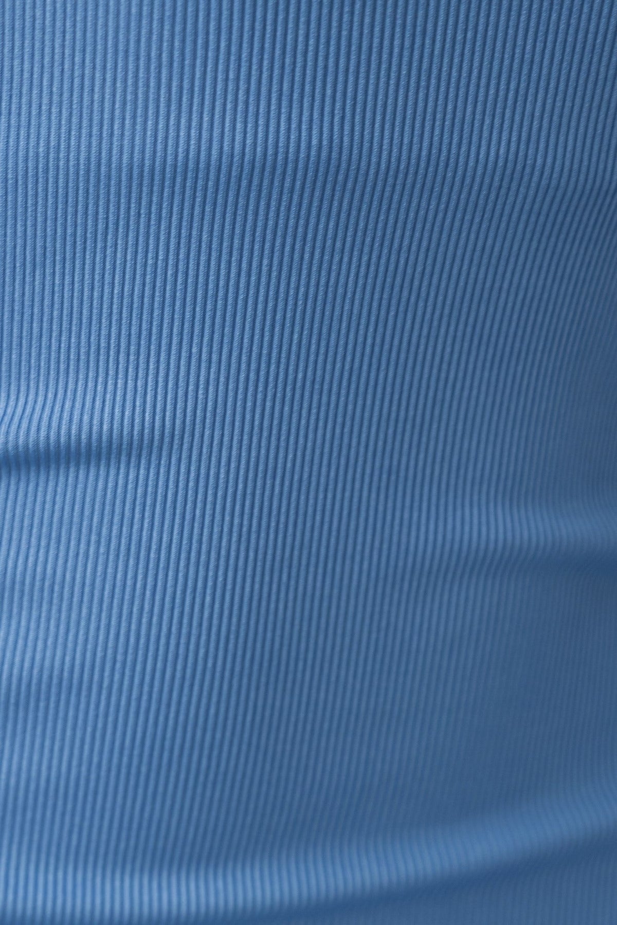 Close-up of ribbed blue fabric, showcasing texture and stretch for fashion items like dresses.