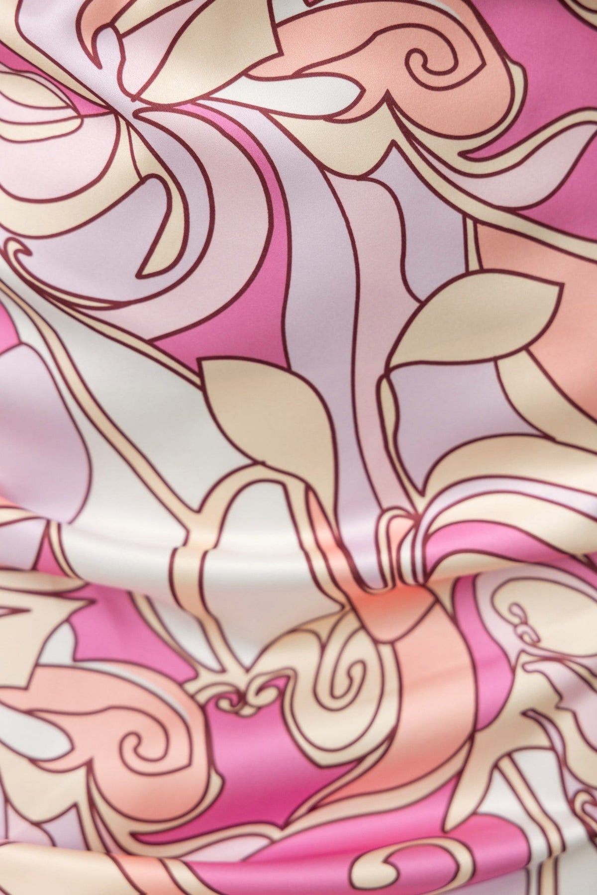 Close-up of pink and cream floral print fabric featuring smooth satin texture, ideal for stylish dresses.