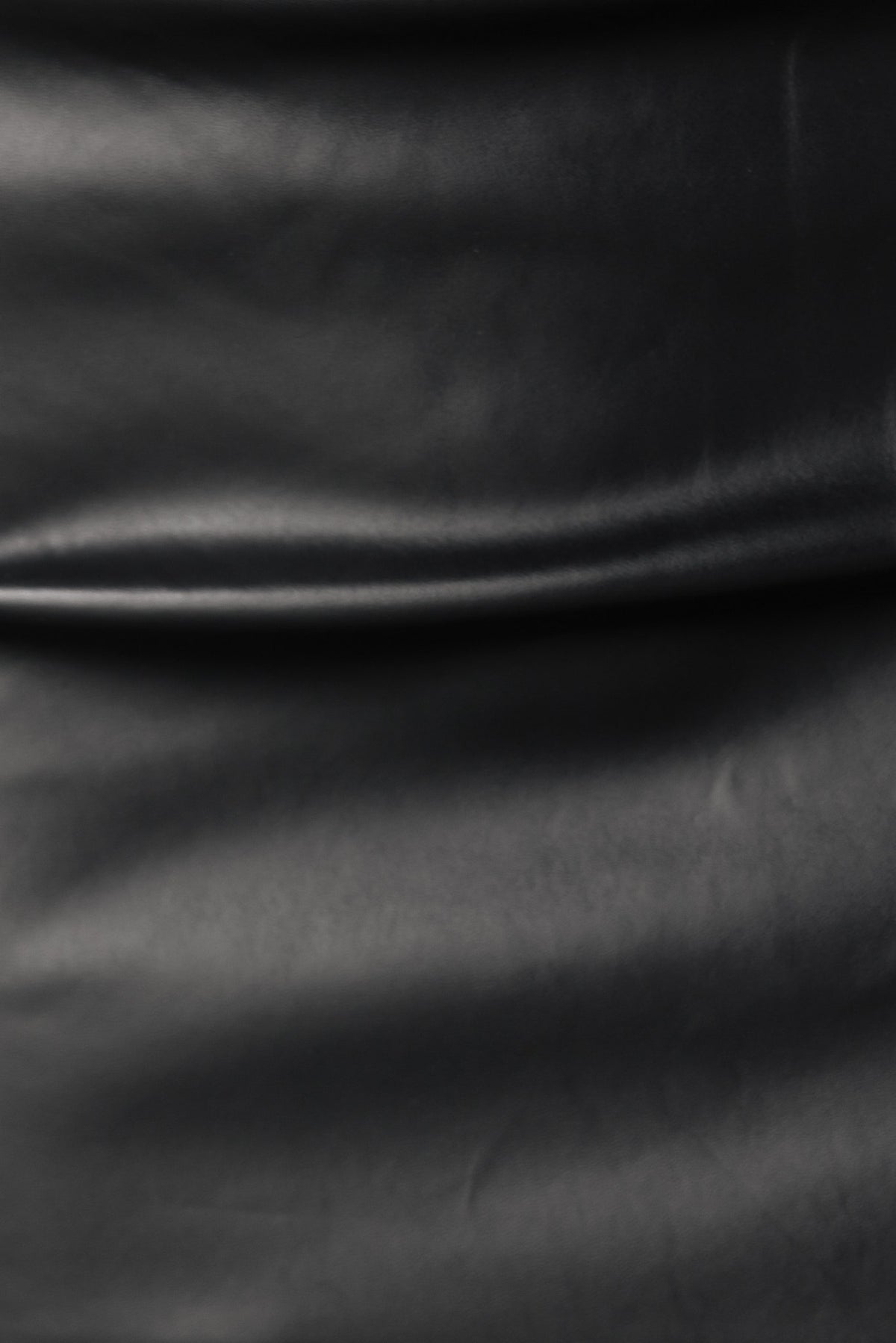 Close-up of black faux leather fabric with smooth texture, showcasing the luxurious look of the Tinashe Top.