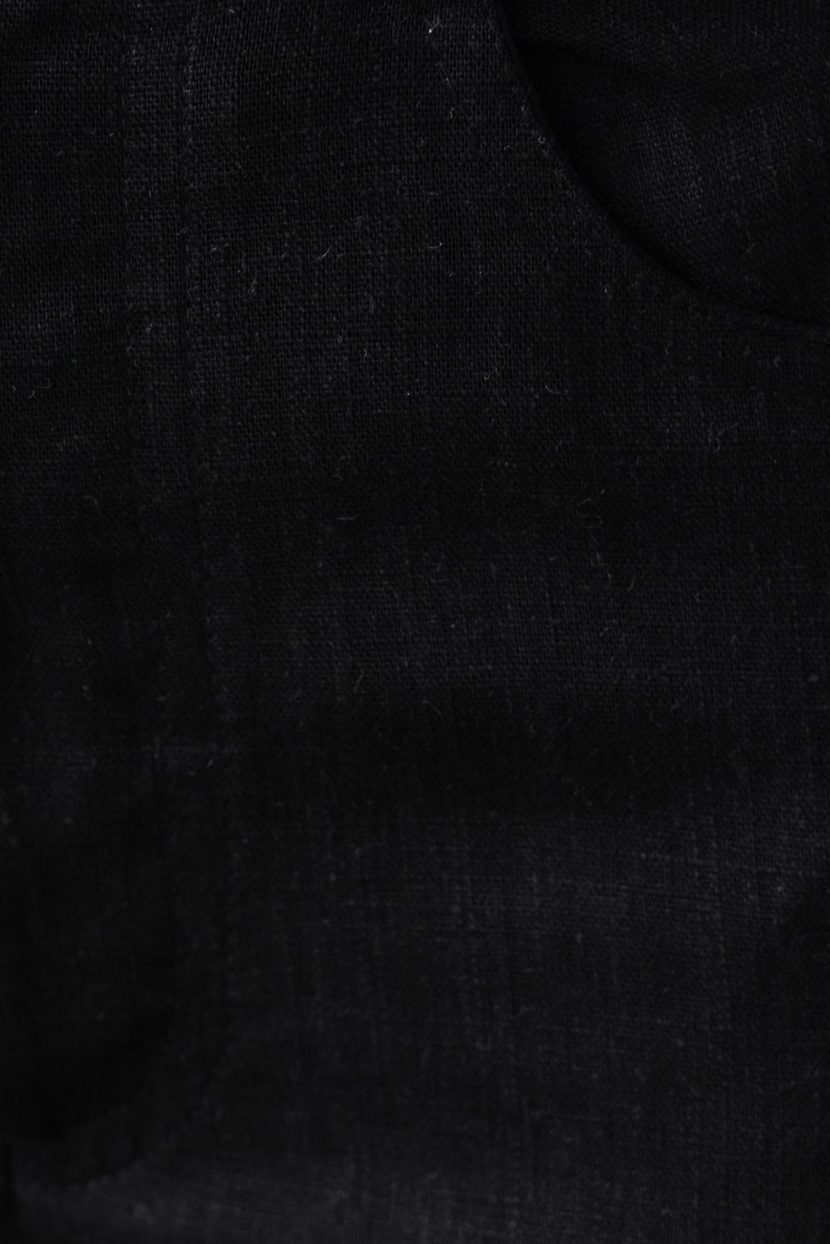 Close-up of Aleo Pants fabric showing black linen texture with a mid-high waist fit and front pocket.