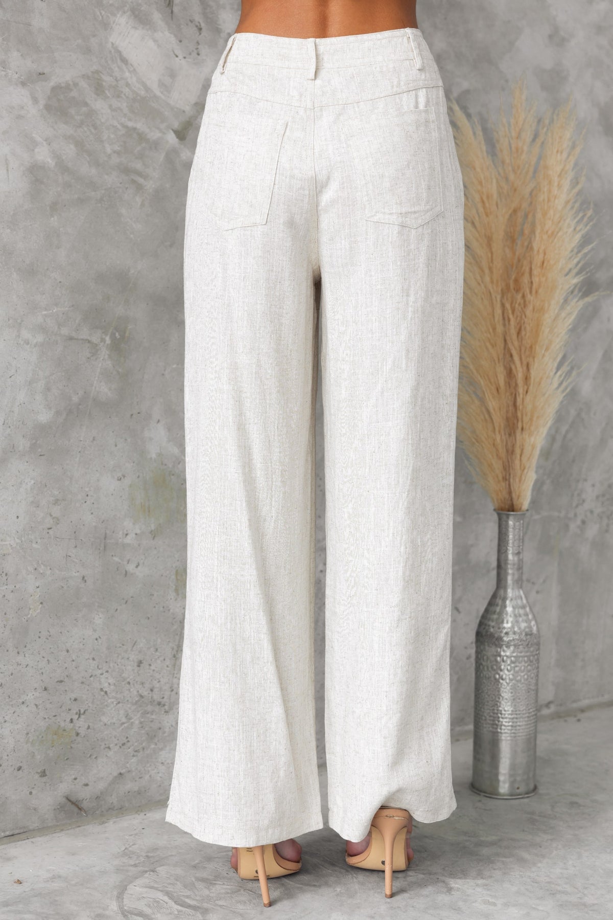 Aleo Pants in a mid-high waist fit, showcasing a linen texture and pockets, styled with trendy heels.