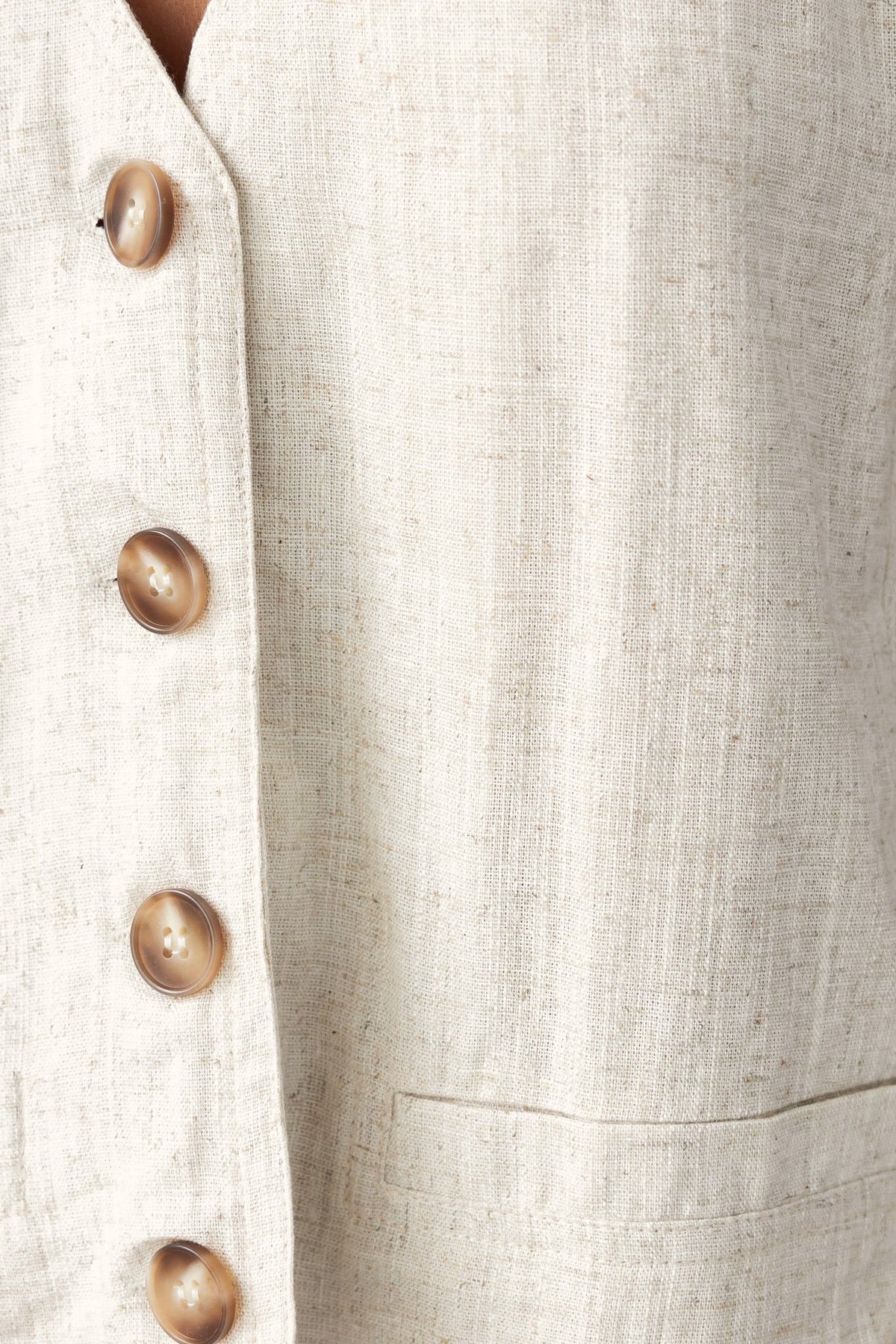 Close-up of linen fabric with buttons, showcasing the texture and neutral color of Aleo Pants.