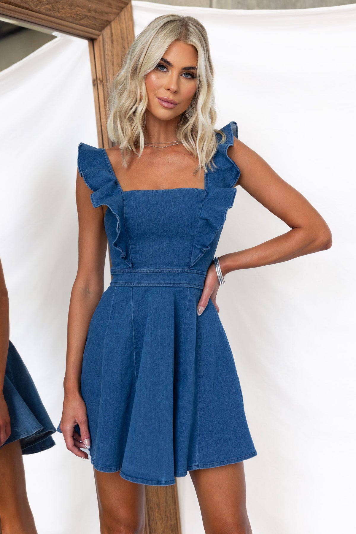 Model wearing a Natty Denim Dress with adjustable straps and ruffled sleeves, showcasing a stylish summer look.