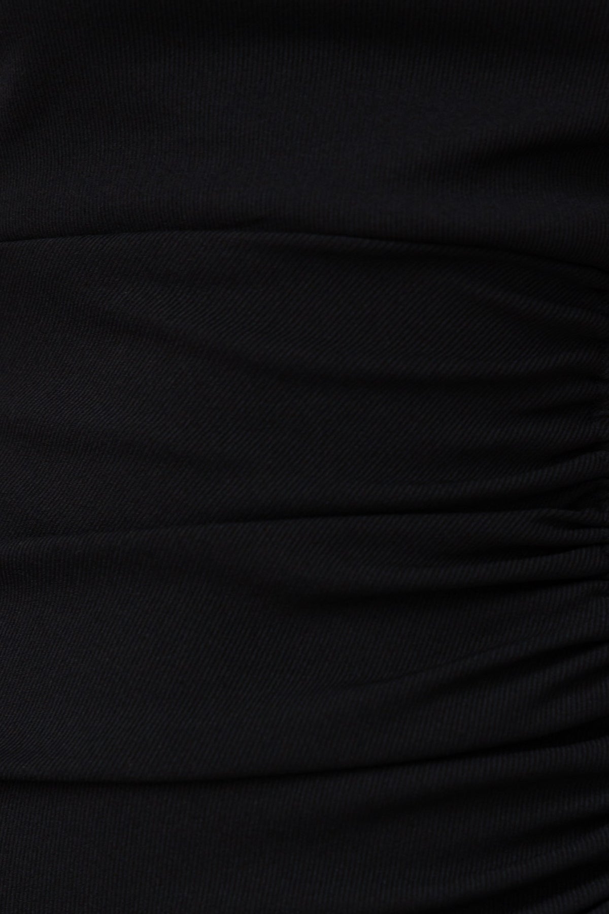 Close-up of the textured fabric detail of the Saber Dress showing black ribbed material with ruching.