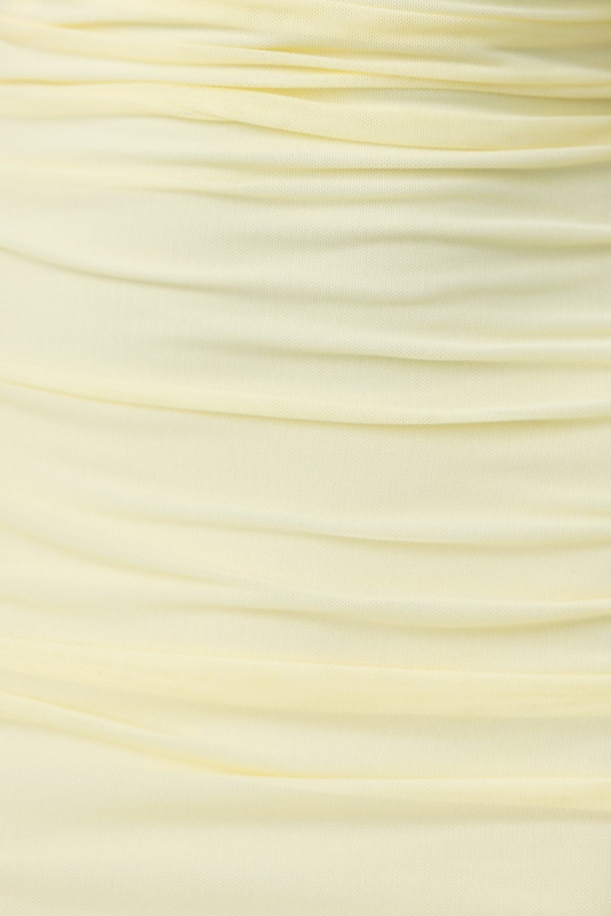 Close-up of soft, draped yellow fabric, showcasing the ruching detail used in the Carlie Maxi Dress design.