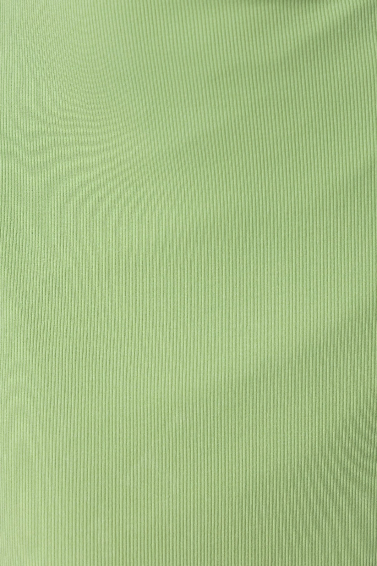 Close-up of ribbed green fabric, showcasing the texture and soft material suitable for stylish clothing.