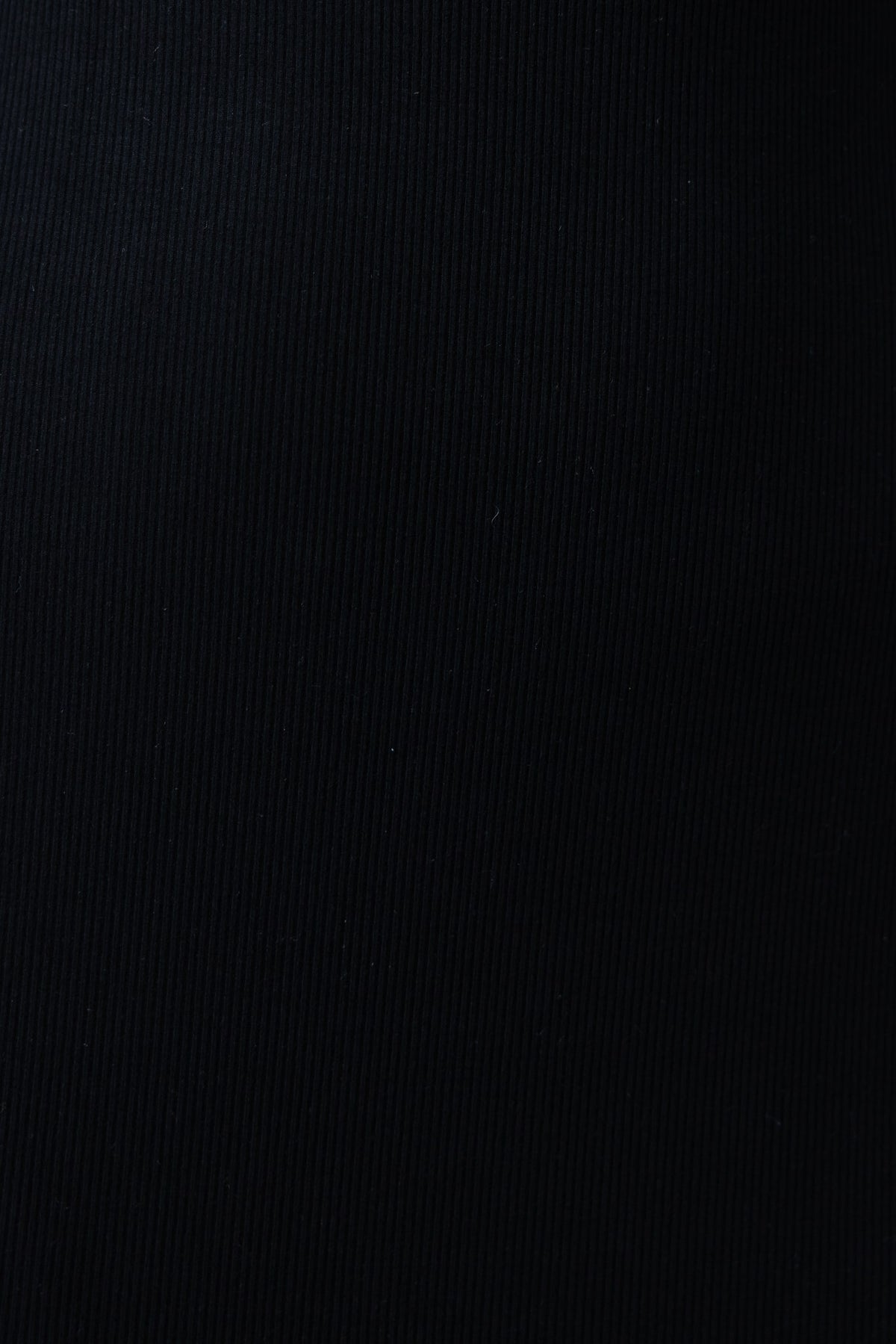 Close-up of textured black ribbed fabric, showcasing the stretch and quality material for a stylish design.