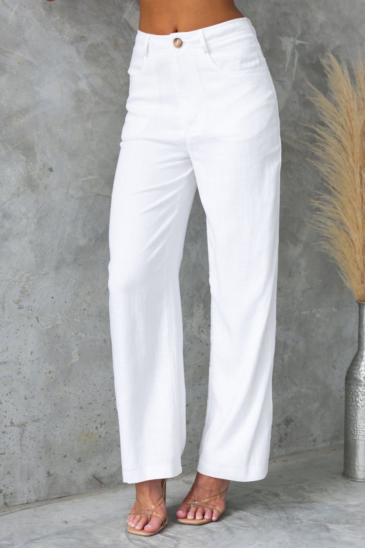 Aleo white linen pants with mid-high waist, front and back pockets, styled for a chic summer look.