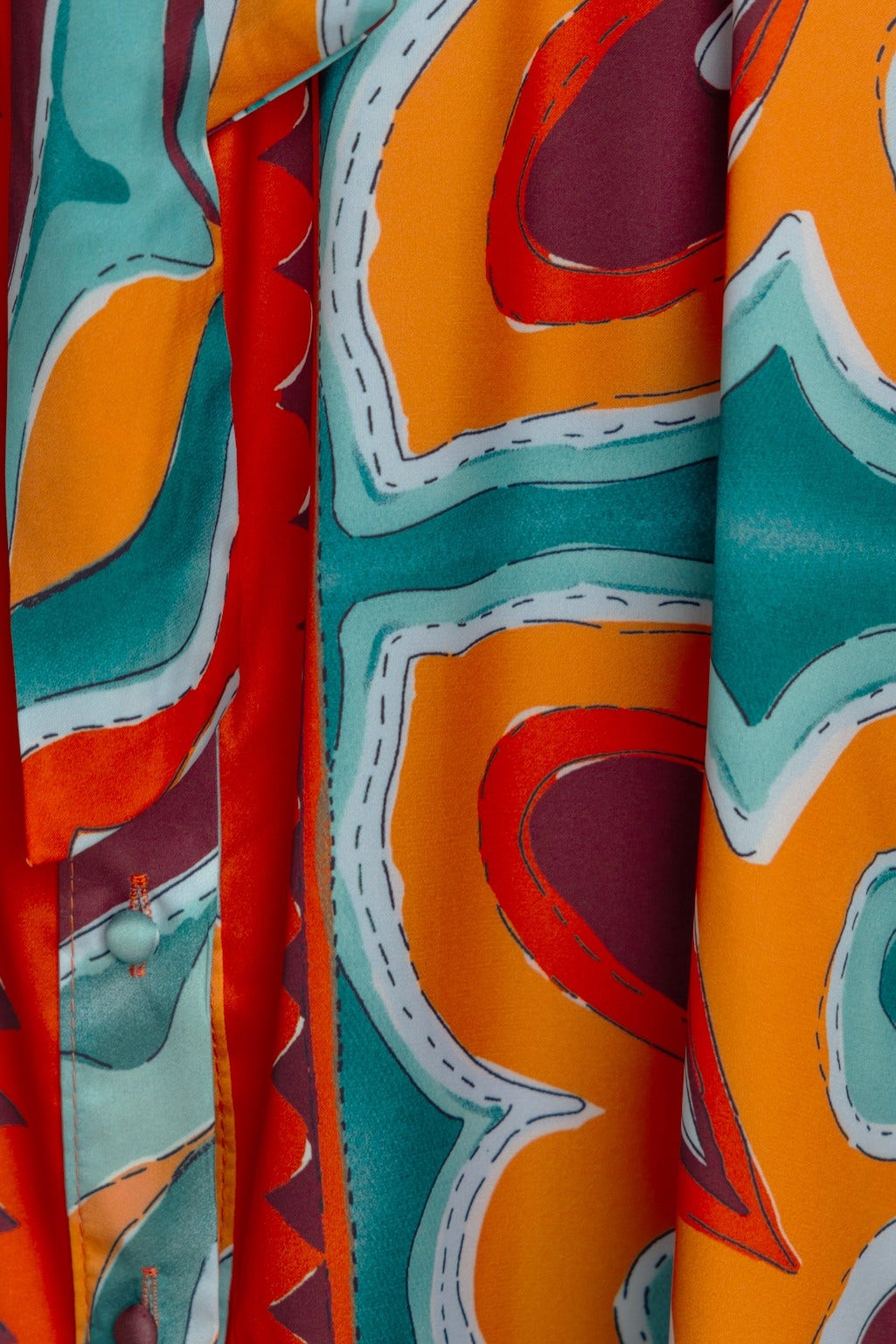 Close-up of abstract print in vibrant orange, teal, and burgundy on Namari Maxi Dress fabric.