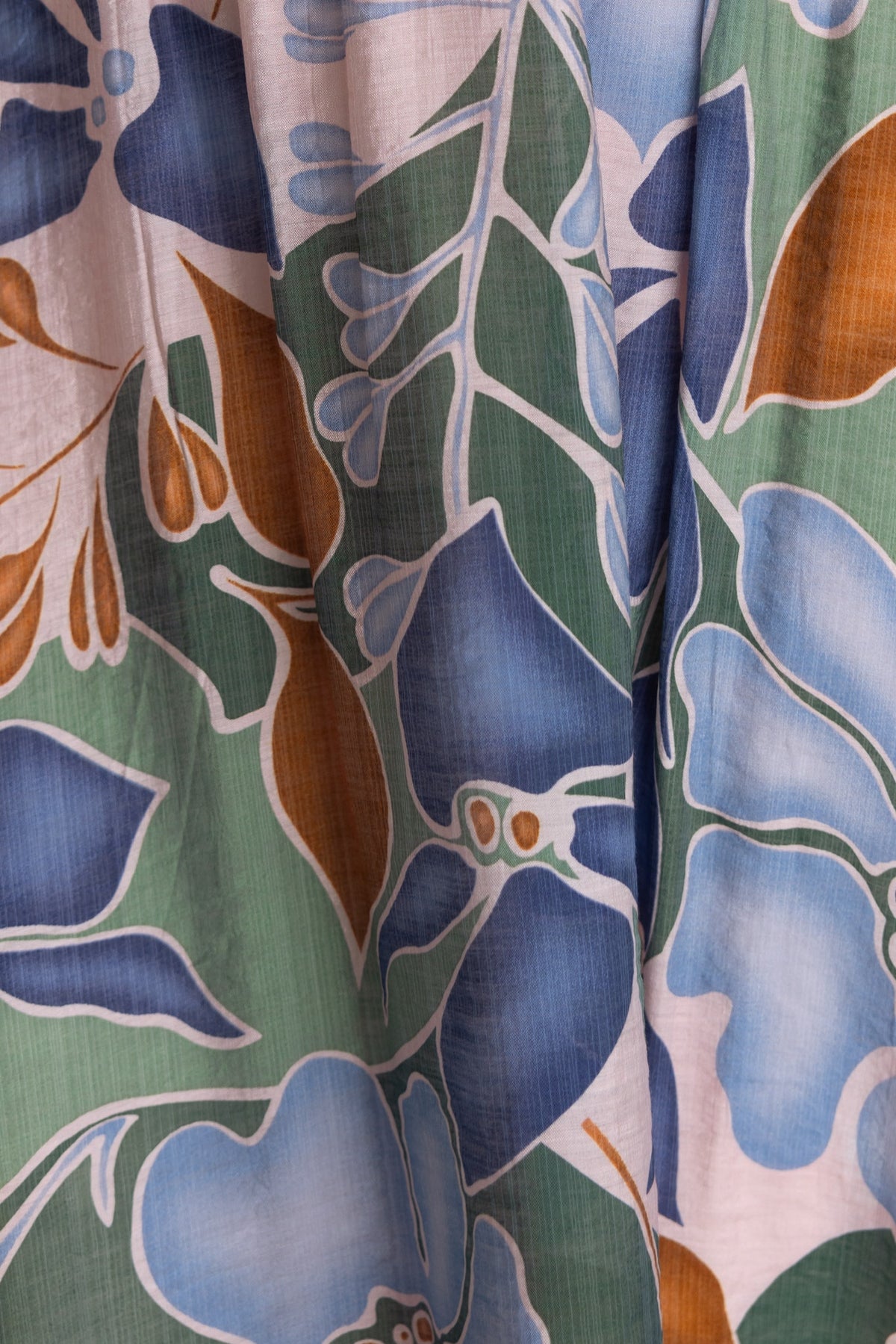 Floral print detail of a Woran midi dress featuring vibrant blue, green, and brown hues on soft fabric.