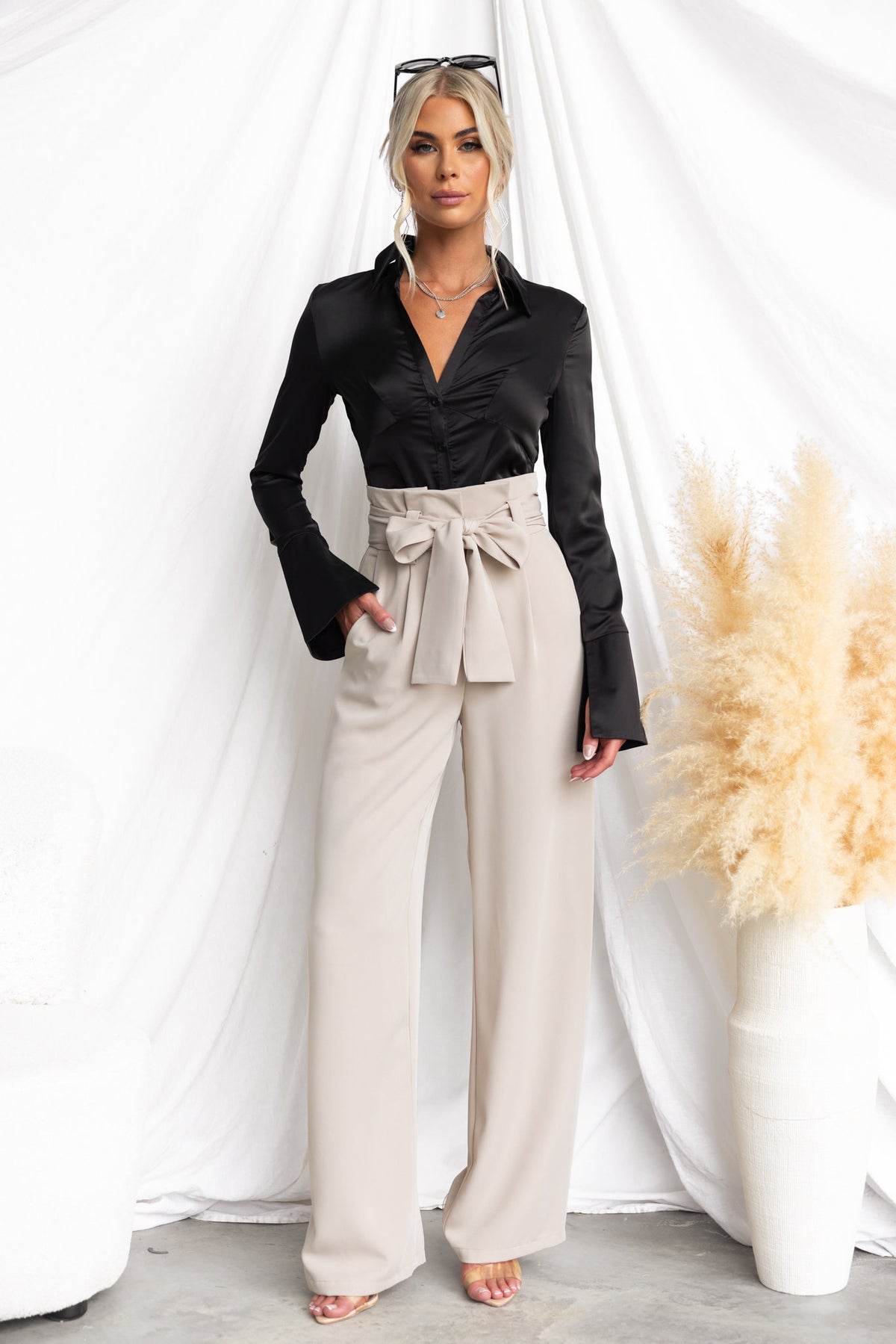 Model wearing Jaspin Pants with paper bag waist and removable tie, styled with a black blouse.