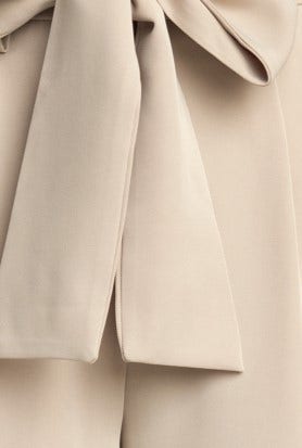 Close-up of the paper bag waist and removable fabric tie detail on Jaspin Pants in a neutral color.