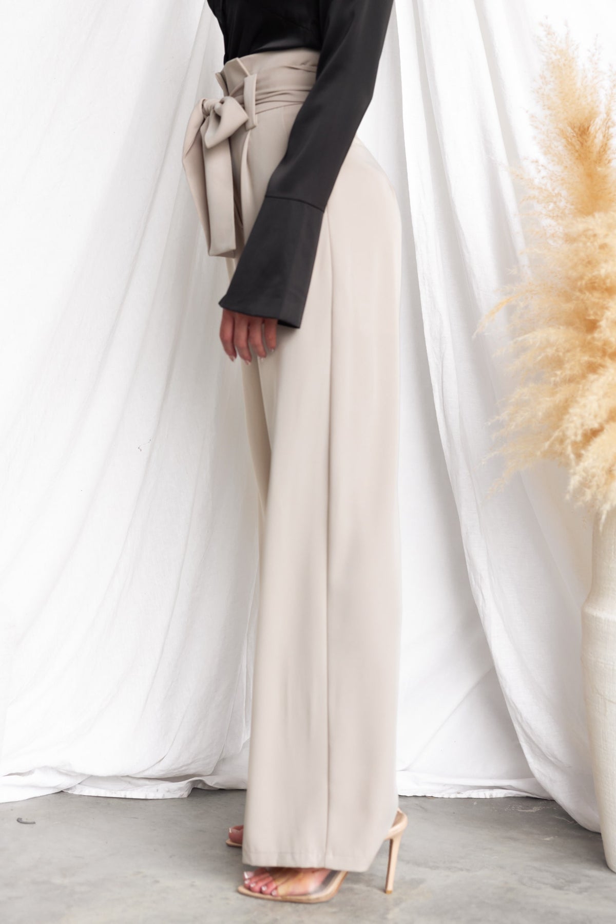 Jaspin Pants featuring a paper bag waist, removable tie, and wide legs in a soft beige color.