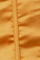 Close-up of the Priya Top in vibrant yellow fabric showing satin texture and zipper detail.