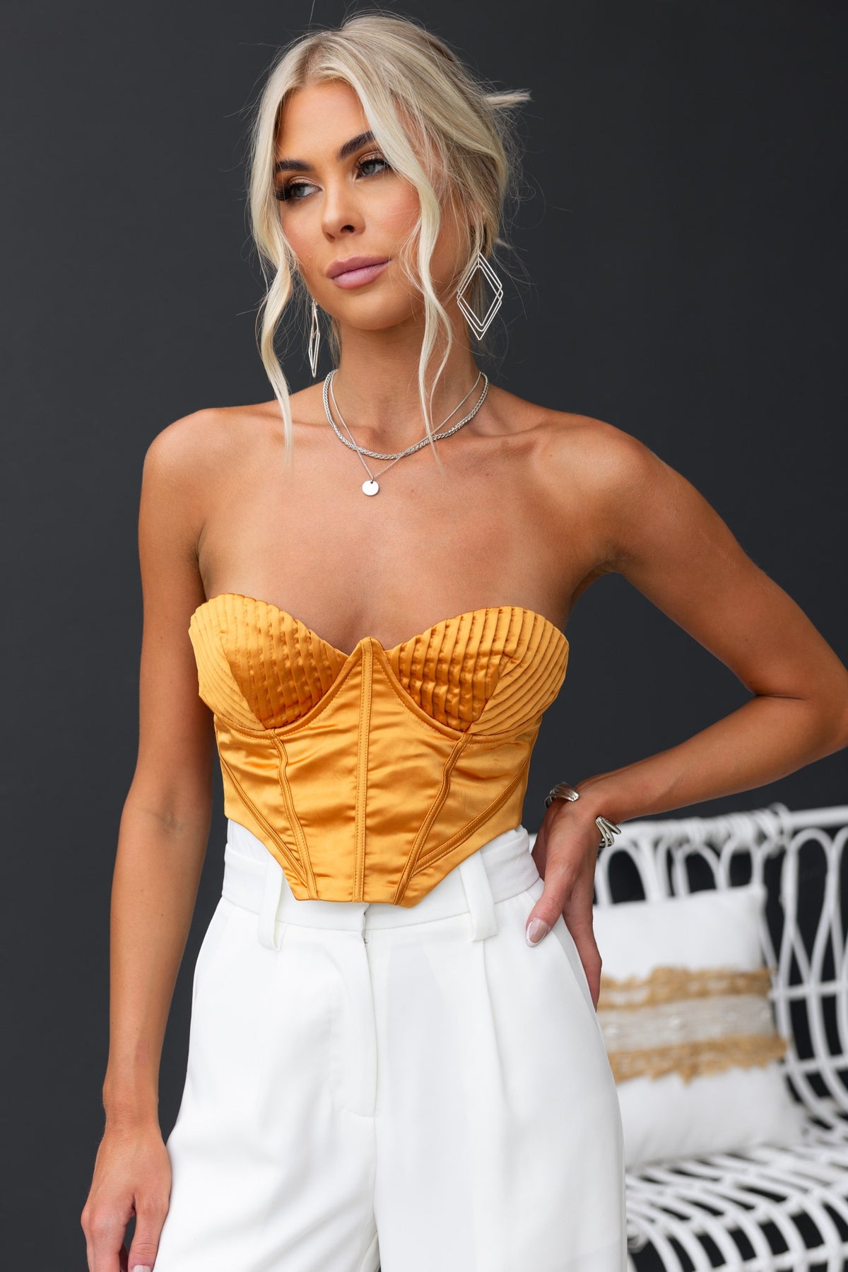 Stylish Priya Top in vibrant yellow, featuring strapless design, boning, and satin finish, paired with white pants.