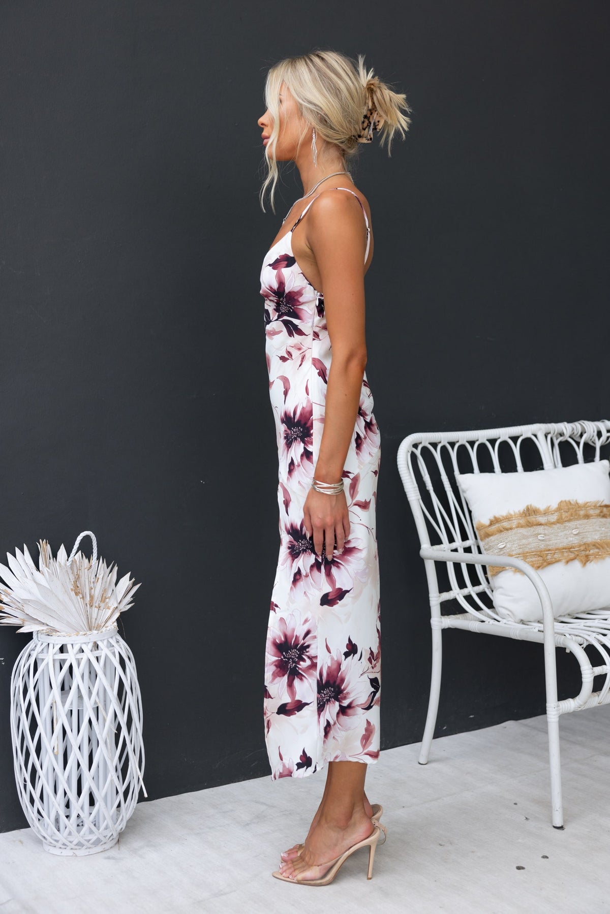 Briley Maxi Dress featuring floral print, adjustable straps, and side split, model styled with heels against a dark background.