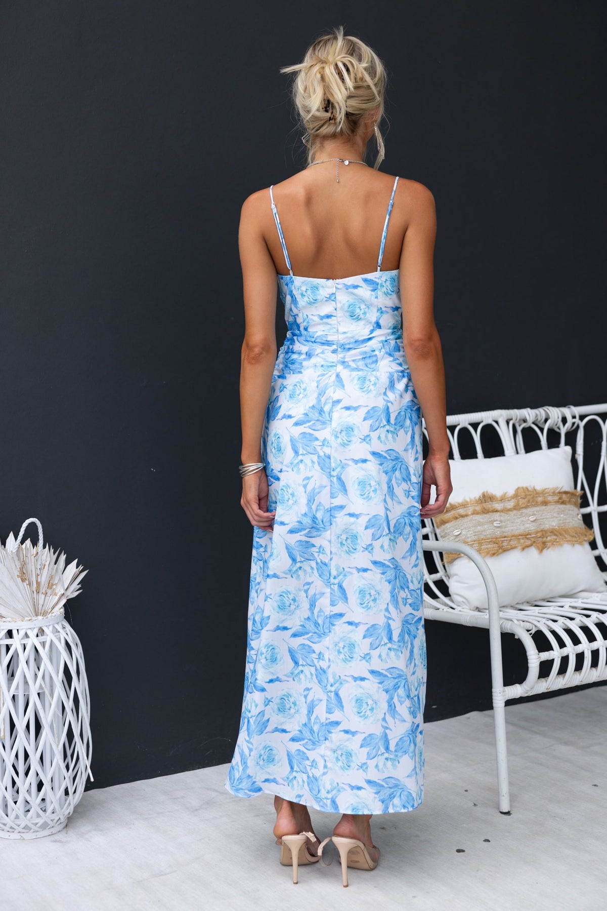 Back view of a floral Genovia maxi dress in blue with adjustable straps and a side split.