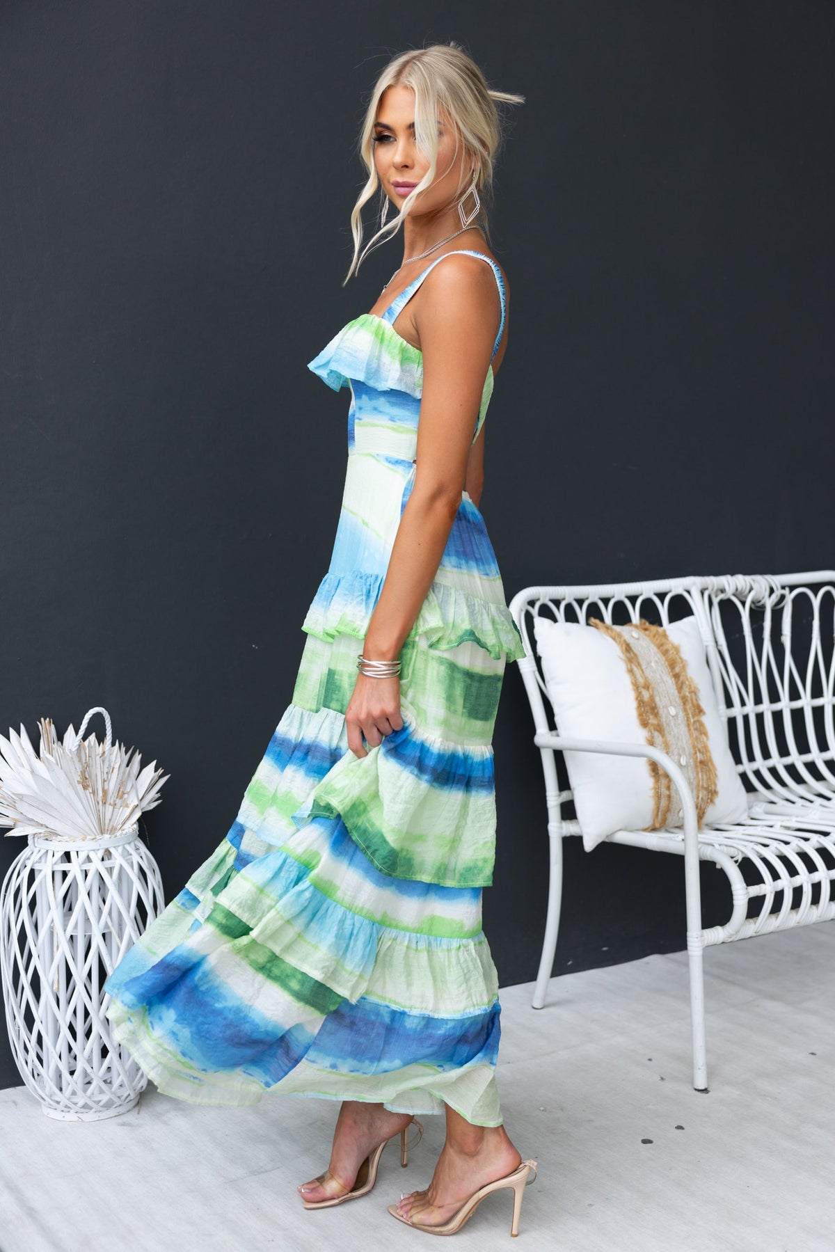 Model wearing the Fondar Maxi Dress with ruffle detail, styled in blue and green stripes, showcasing an elegant summer look.