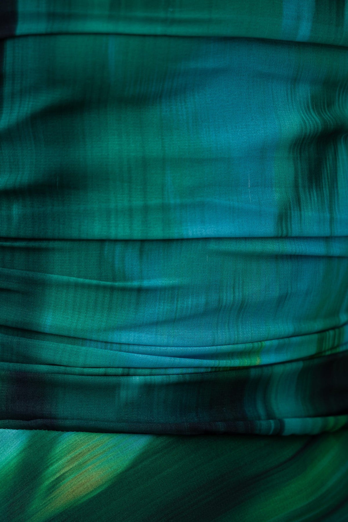 Close-up of the green chiffon fabric featuring a flowing, abstract watercolor design.