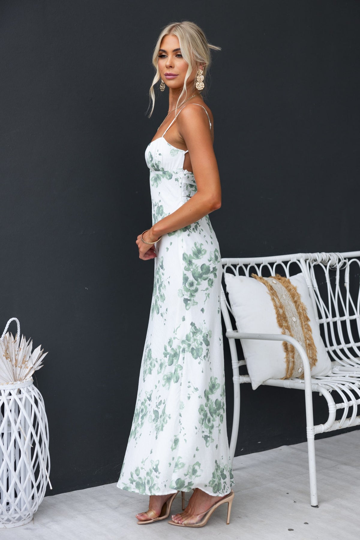 Freyda Maxi Dress featuring floral print, adjustable straps, and cut-out back, styled with sandals and modern decor.